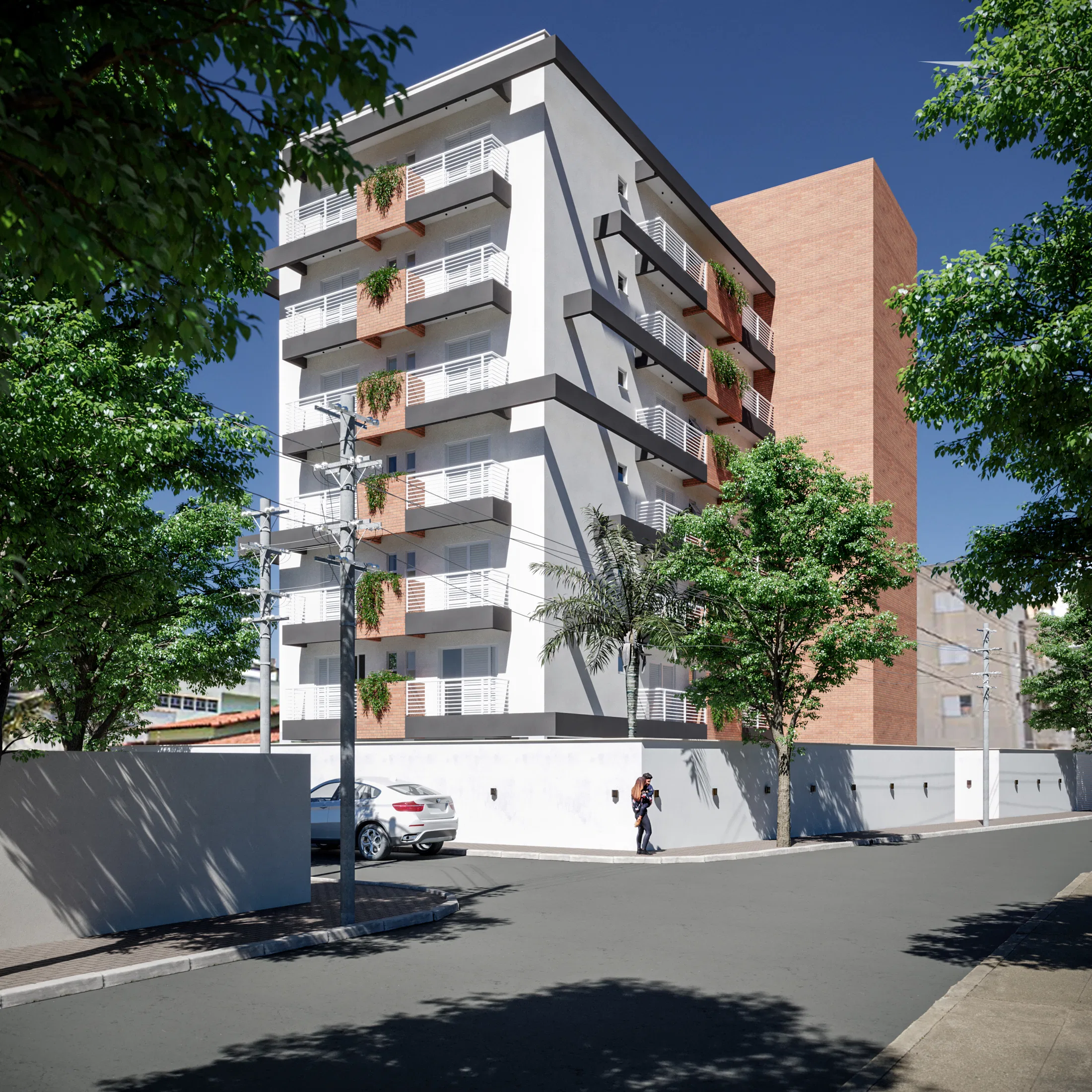Vista de esquina de um edifício de vários pavimentos, com fachada branca de sacadas escalonadas e vegetação pendente, volume lateral em tijolo e muro branco na calçada