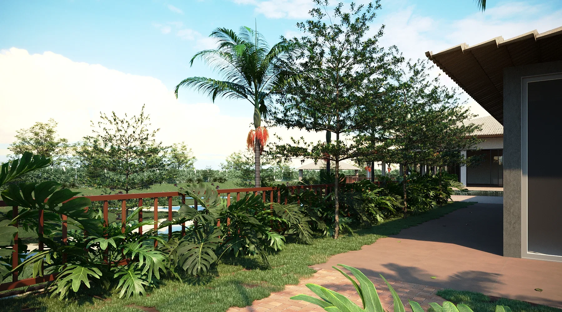 Jardim visto de um deck com guarda-corpo de madeira, com folhagens tropicais, palmeira florida e caminho de tijolinho seguindo até a casa.