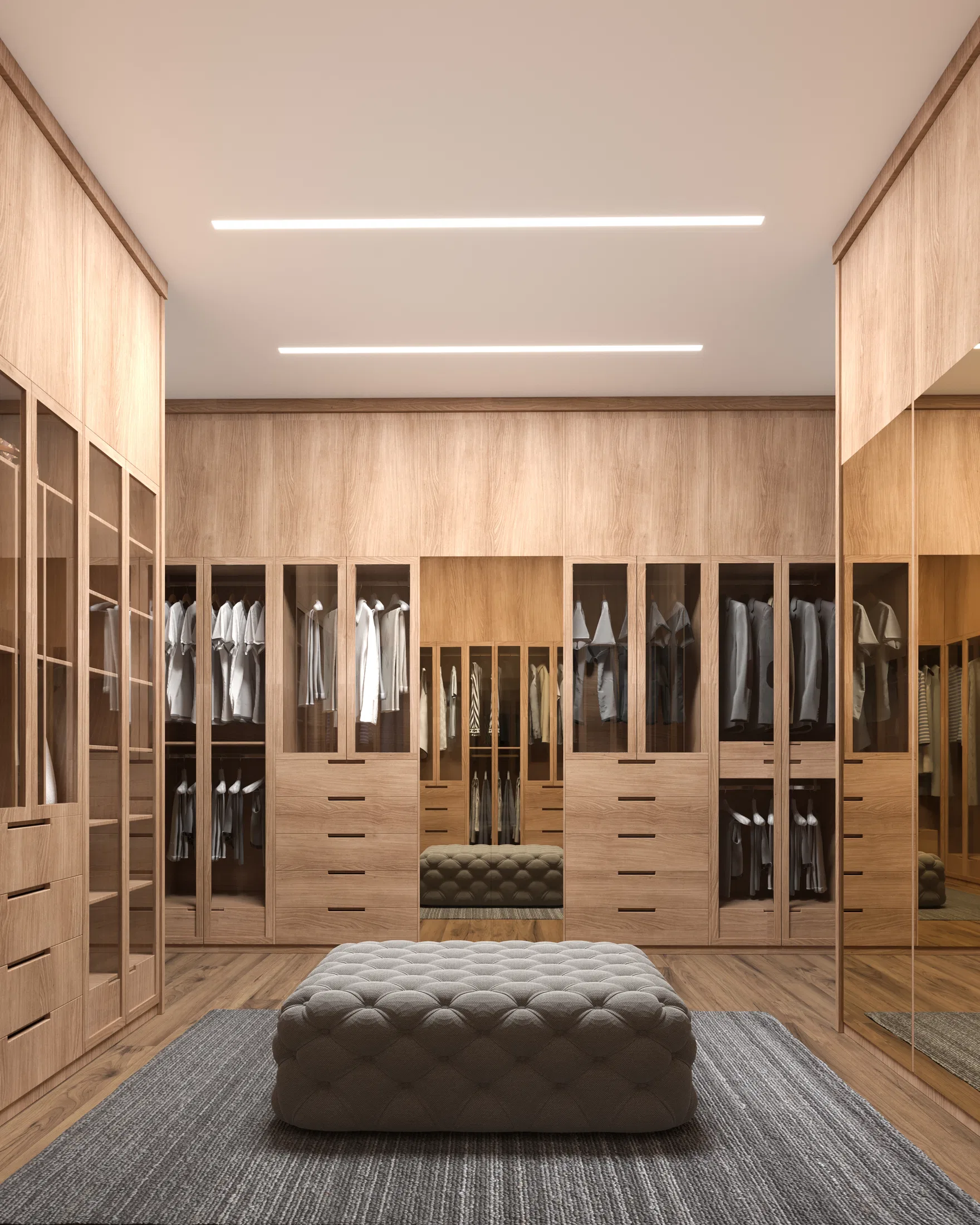 Closet amplo com armários de madeira clara e portas envidraçadas revelando roupas penduradas, puff estofado capitonê ao centro sobre tapete cinza e fitas de LED no teto